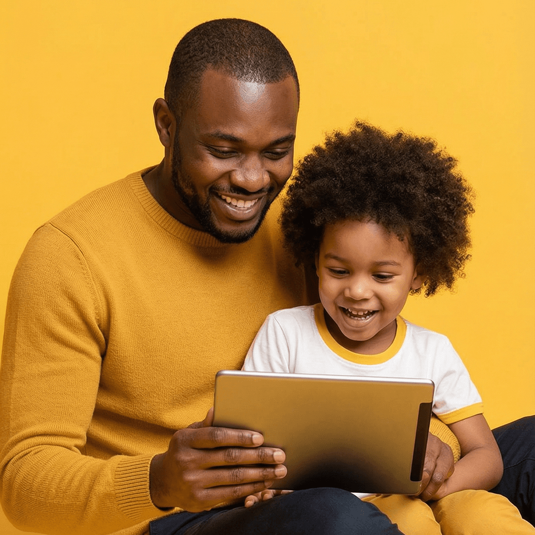 A smiling Black man and child look at a tablet together.